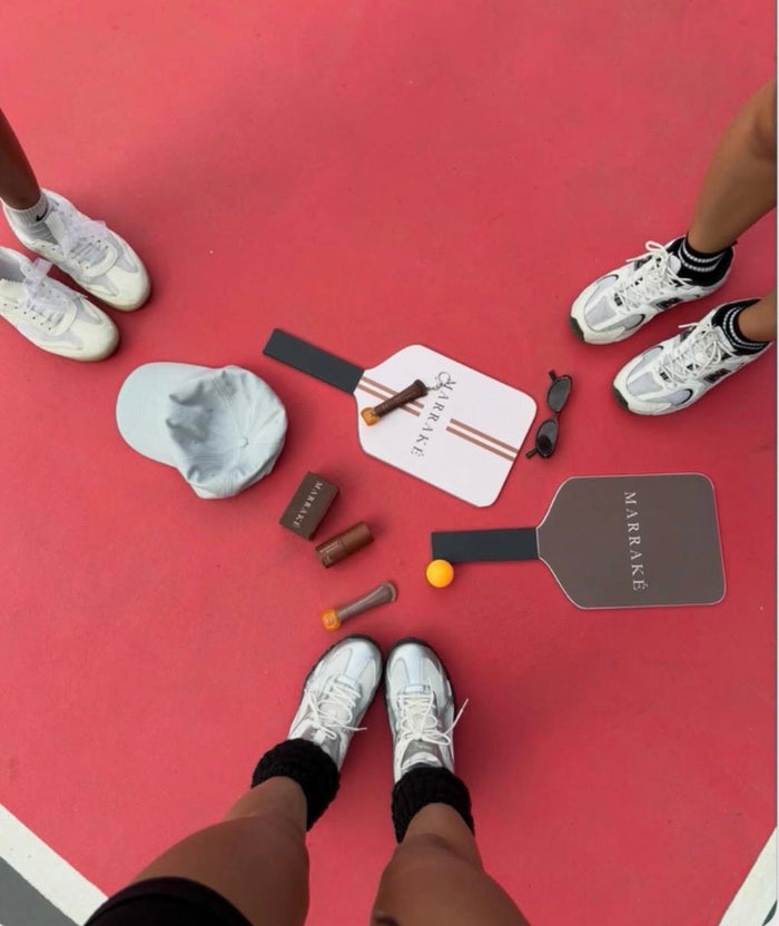 Marraké products and pickleball paddles on a red court